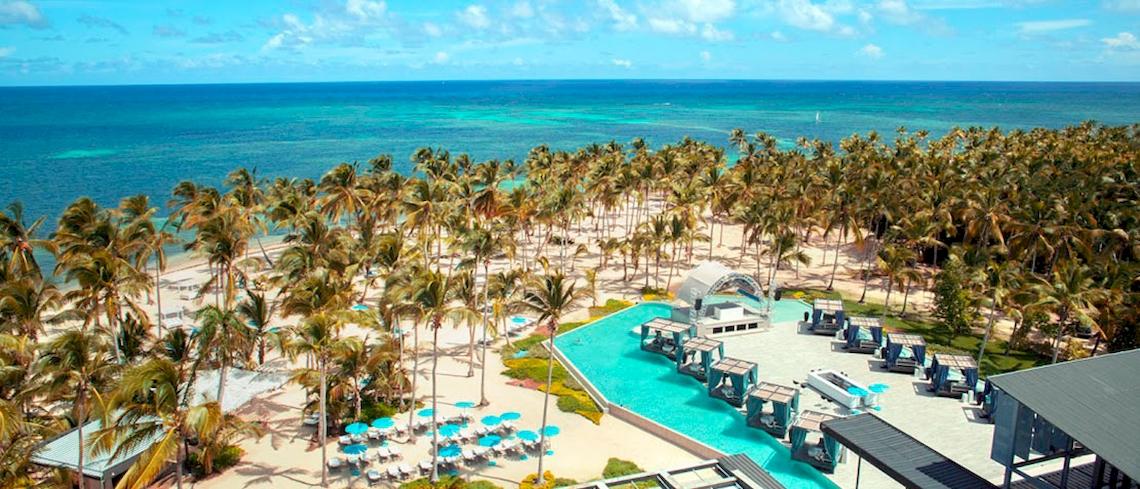 Luftaufnahme des Catalonia Royal Bavaro Resorts mit Pool, Sonnenliegen und Palmen am Strand.