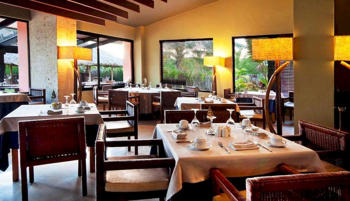 Innenansicht des Restaurants im Catalonia Royal Bavaro Hotel mit gedeckten Tischen und Stühlen.