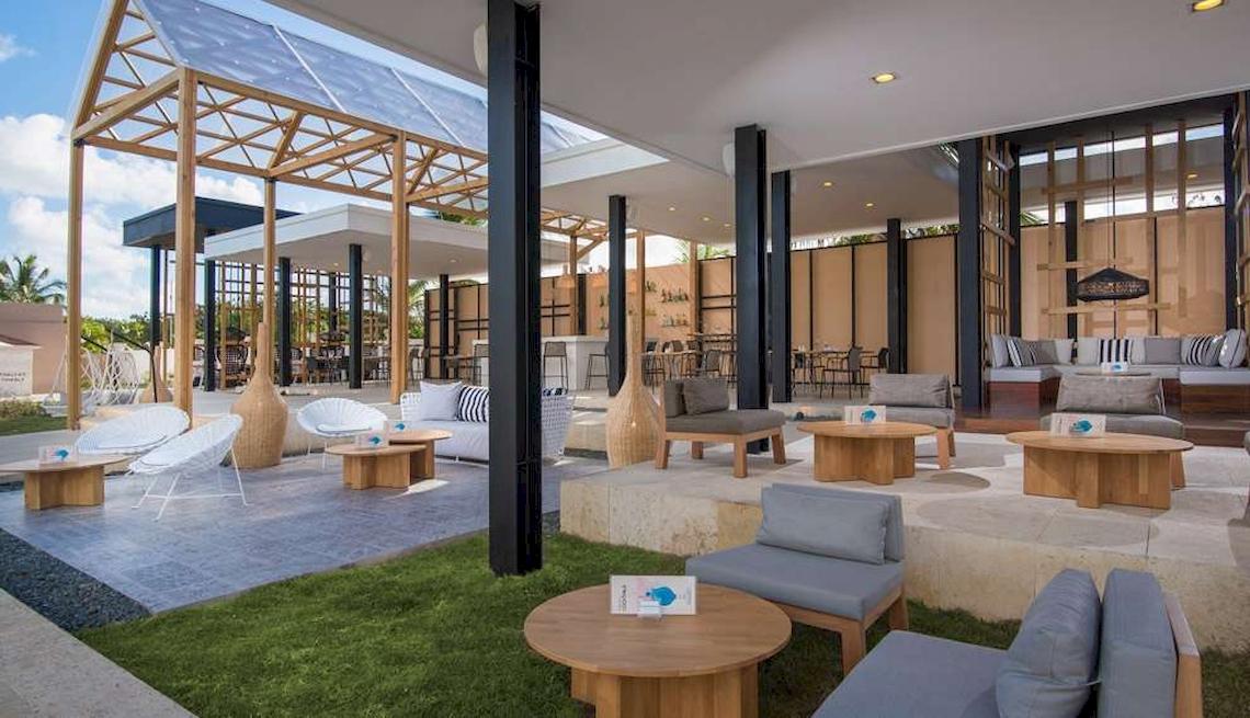 Terrasse des Catalonia Royal Bavaro Hotels mit Holztischen und Stühlen.