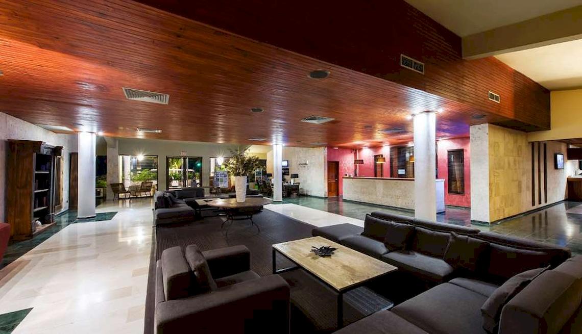 Innenbereich des Catalonia Royal Bavaro Hotels mit Sofas, Tischen und Holzdecke.