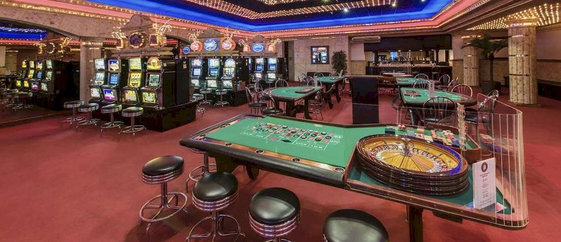 Spielbereich im Casino des Catalonia Royal Bavaro Hotels mit Roulettetisch, Spielautomaten und Tischen.