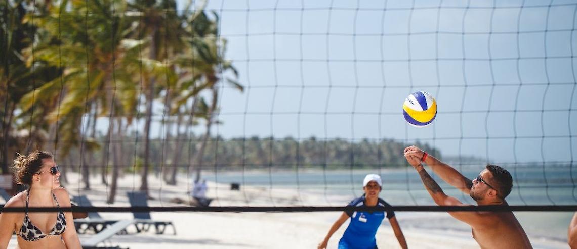 Volleyballspiel am Strand des Catalonia Royal Bavaro Hotels mit Spielern und Zuschauern.
