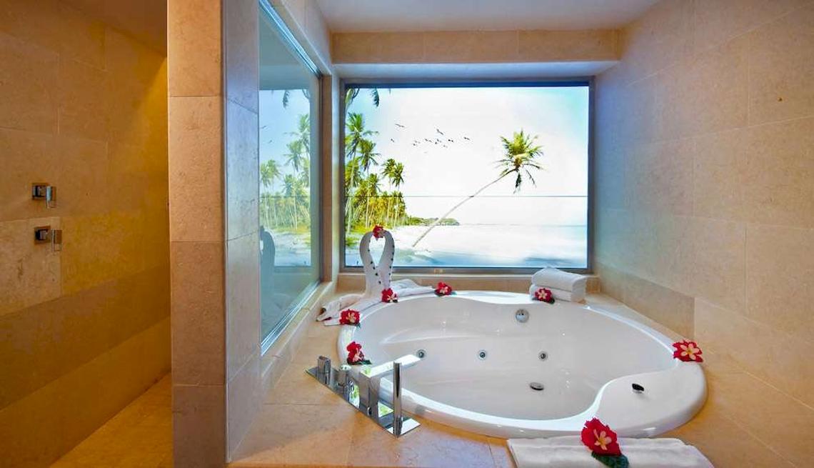 Ein Badezimmer im Catalonia Royal Bavaro Hotel mit großer Badewanne und Panoramafenster zum Meer.