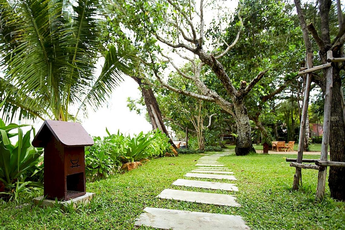 Gartenweg im Tubkaak Krabi Boutique Resort mit grünem Rasen und Bäumen.