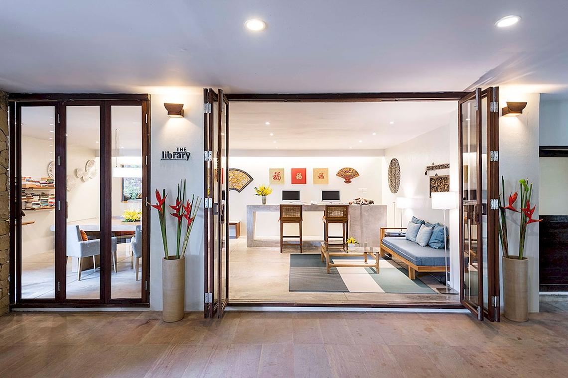 Eingangsbereich der Bibliothek im Tubkaak Krabi Boutique Resort mit offenen Türen und Inneneinrichtung.