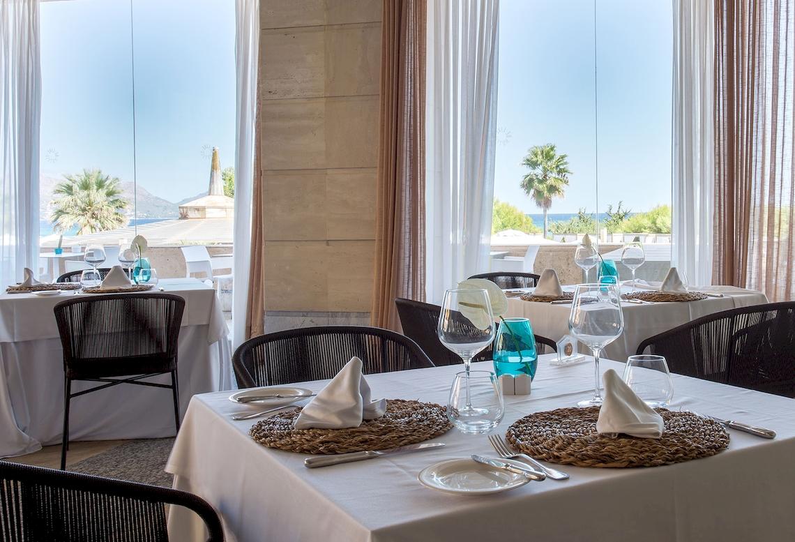 Innenansicht des Restaurants des Sarena de Muro Resort Mallorca mit Tischen und Blick auf den Ozean.