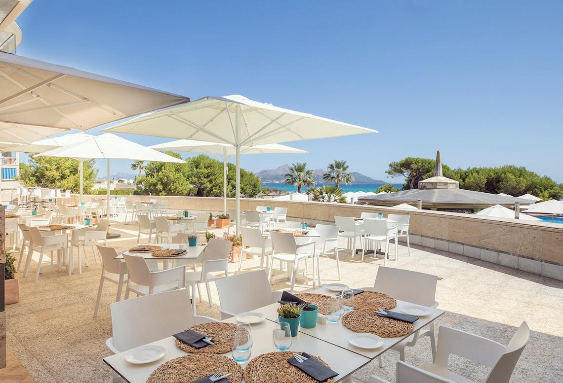 Terrasse des Sarena de Muro Resorts auf Mallorca mit Tischen, Stühlen und Sonnenschirmen