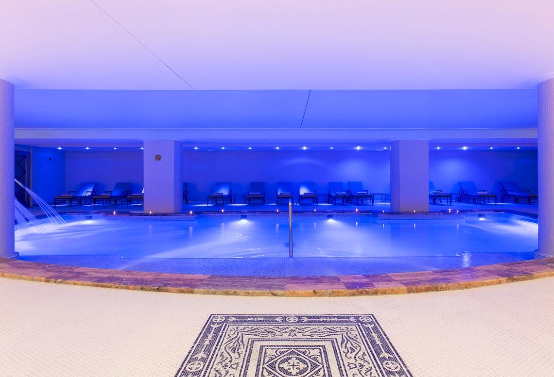 Innenpool des Sarena de Muro Resort Mallorca mit blauer Beleuchtung und Liegestühlen