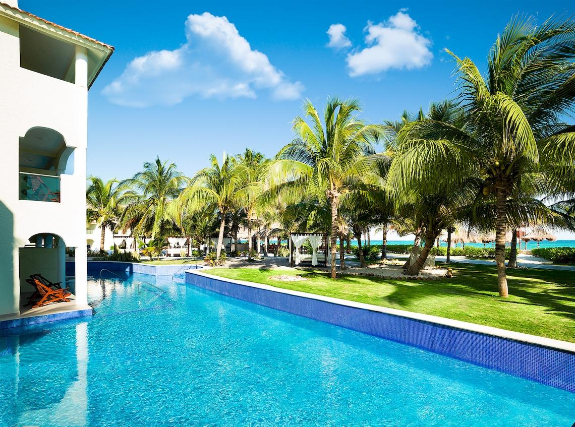 Pool mit Palmen und Strand am El Dorado Royale Spa Resort by Karisma