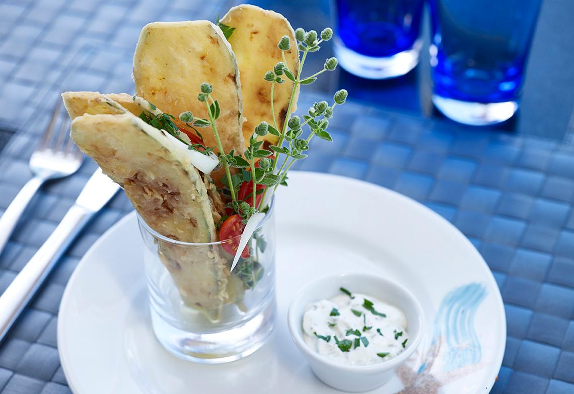 Ein Gericht im Serita Beach Hotel mit frittierten Tortilla-Chips, Tomaten und Kräutern in einem Glas auf einem Teller.