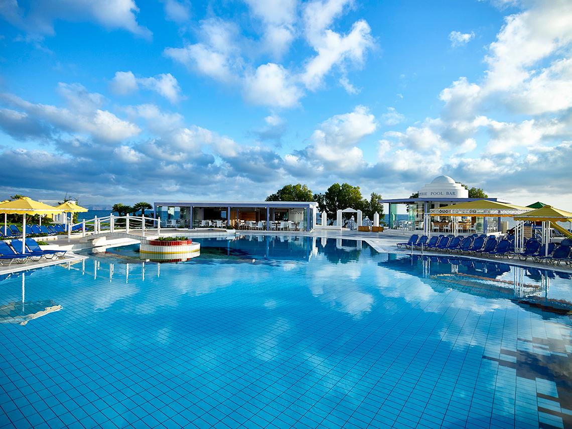 Außenpool des Serita Beach Hotels mit Lounge-Stühlen und gelben Sonnenschirmen