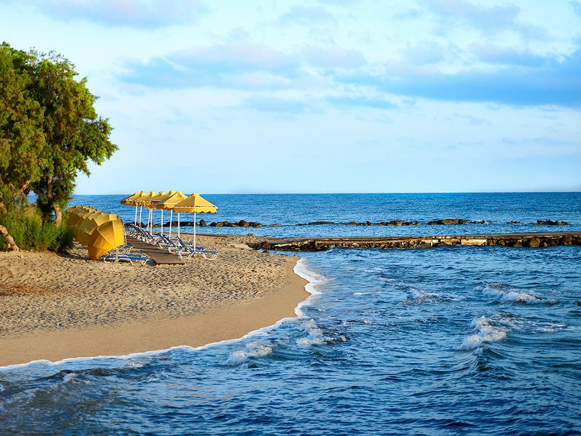 Strand des Serita Beach Hotels mit Sonnenliegen, Sonnenschirmen und Meer