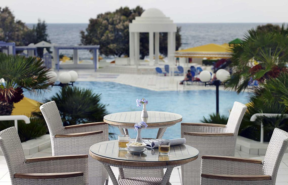 Außenterrasse des Serita Beach Hotels mit Blick auf den Pool und das Meer.