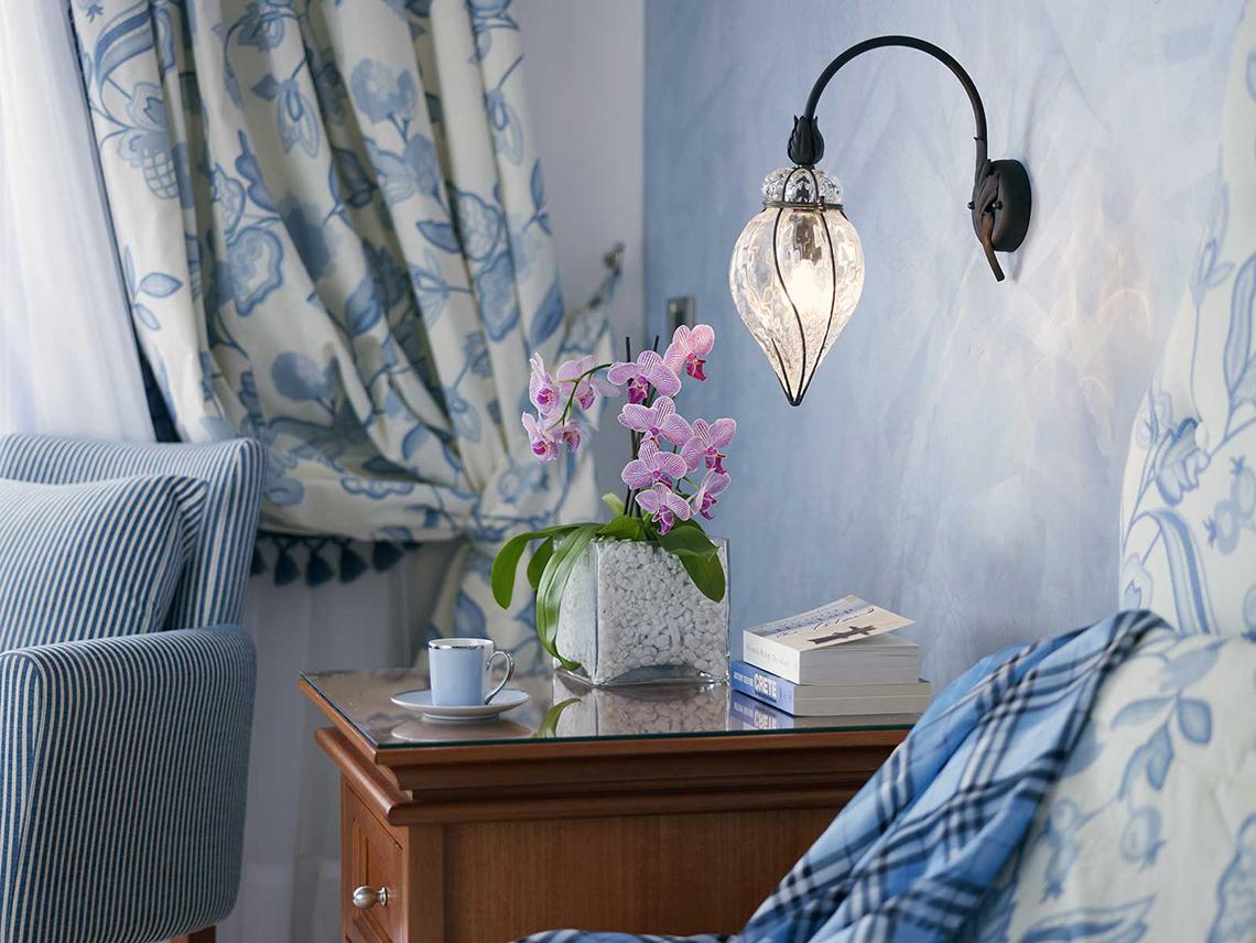 Serita Beach Hotel Zimmer mit Nachttisch, Orchideen, Bücher und Wandlampe.