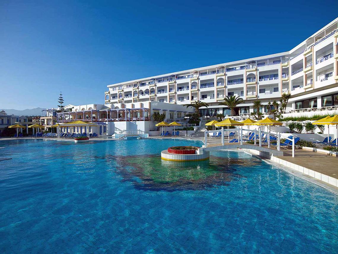 Außenpool des Serita Beach Hotels mit Sonnenliegen und gelben Sonnenschirmen.