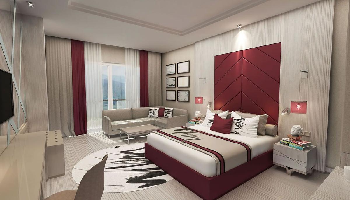 Designer Schlafzimmer im Delphin BE Grand Resort mit einem großen Bett, einem roten Kopfteil und einer gemütlichen Sitzecke.