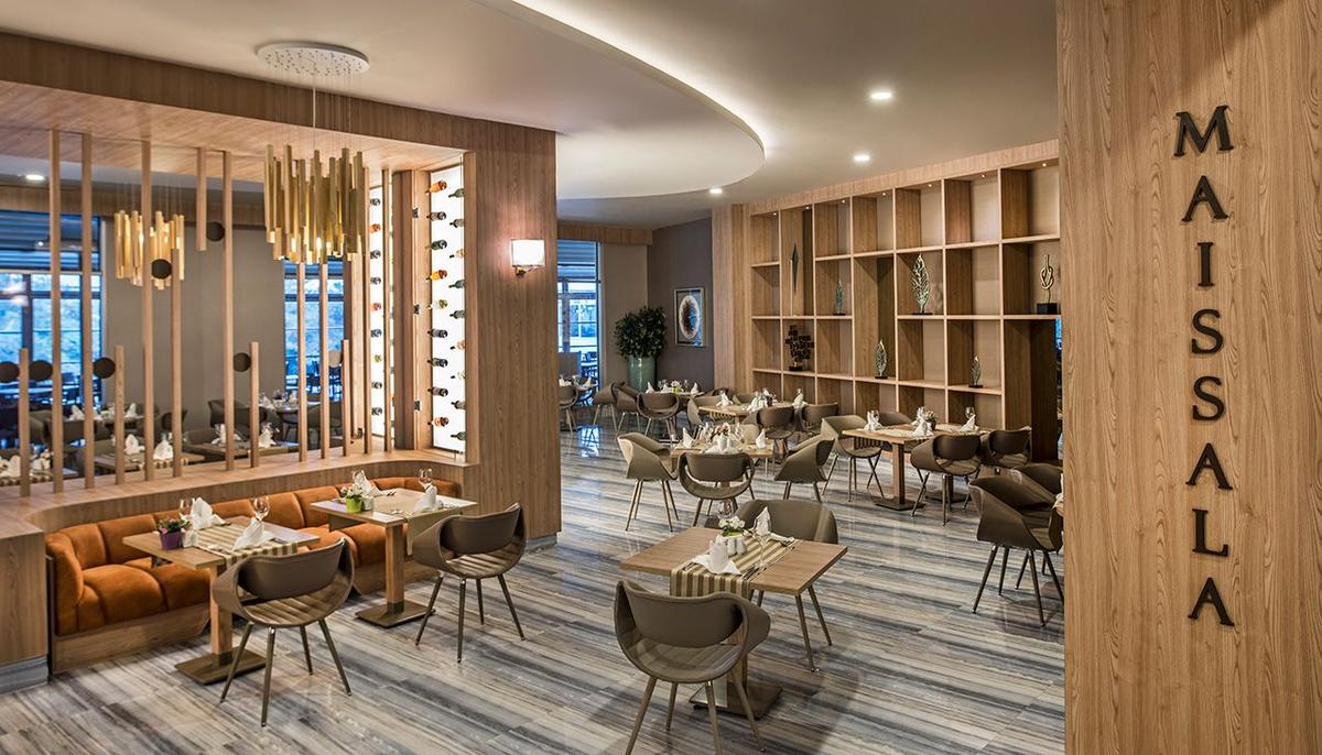 Innenansicht des Restaurants im Delphin BE Grand Resort mit Holzelementen und modernen Möbeln.