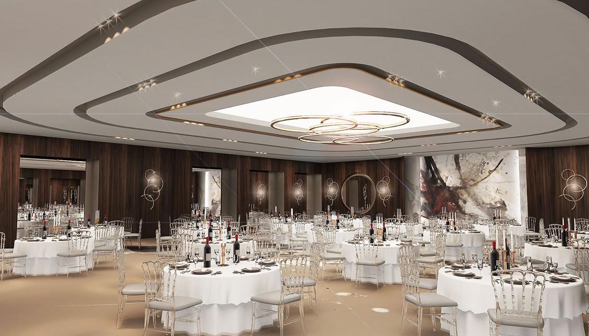 Bankettsaal des Delphin BE Grand Resort mit vielen gedeckten Tischen und einer großen zentralen Lichtinstallation.