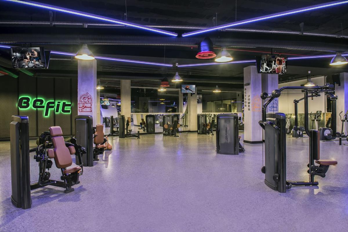Fitnessstudio im Delphin BE Grand Resort mit moderner Ausstattung und neonfarbenen Befit-Schildern.
