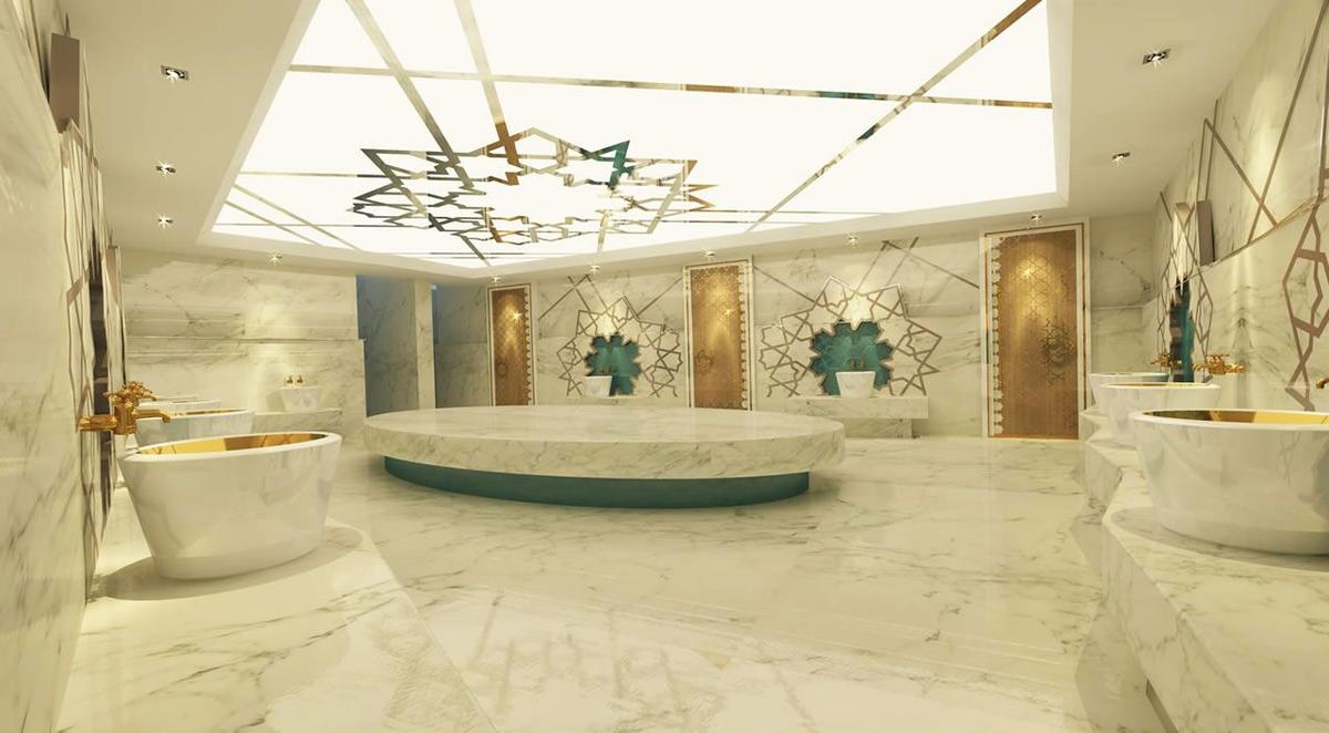Das Badezimmer des Delphin BE Grand Resort mit Marmorboden und Wänden, goldenen Armaturen und einer zentralen Wanne.