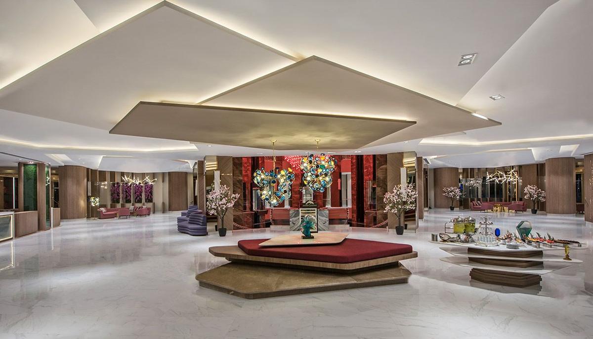Lobby des Delphin BE Grand Resort mit Marmorboden, modernen Möbeln und Kunstwerken.