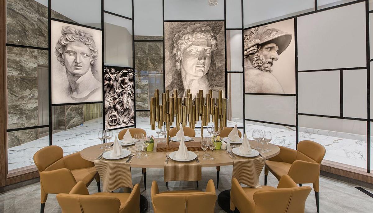 Speisesaal im Delphin BE Grand Resort mit klassischen Kunstwerken an den Wänden und runden Tisch.