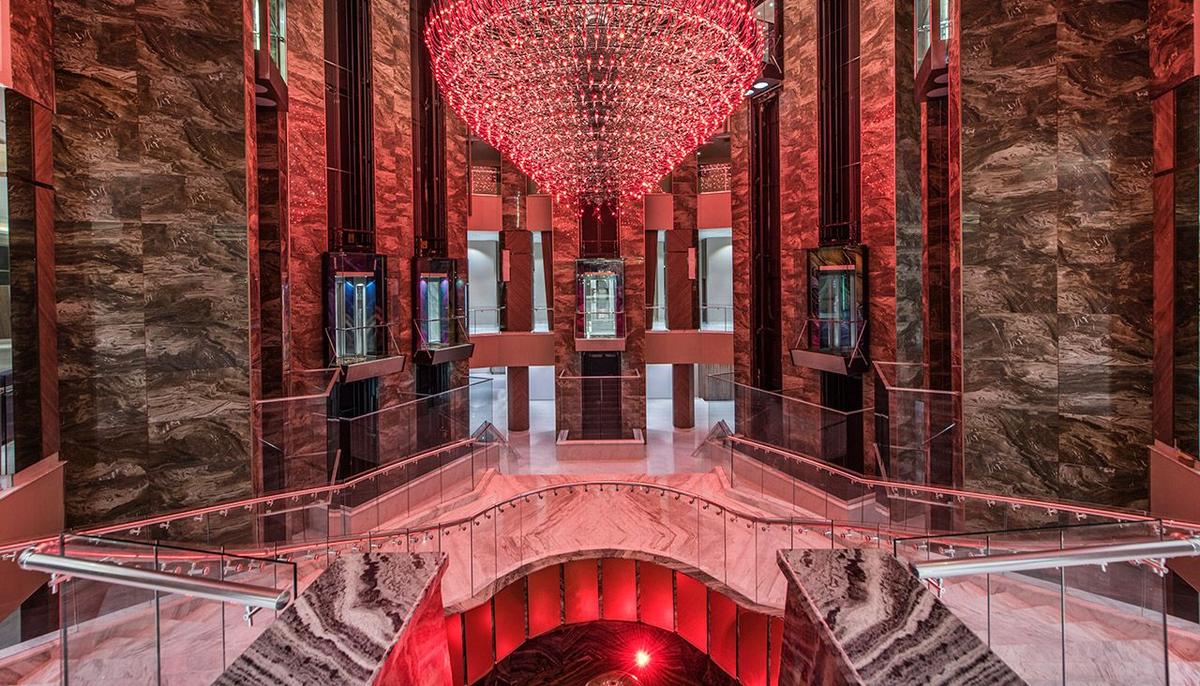 Lobby des Delphin BE Grand Resort mit einer großen roten Beleuchtung und Marmorwänden.