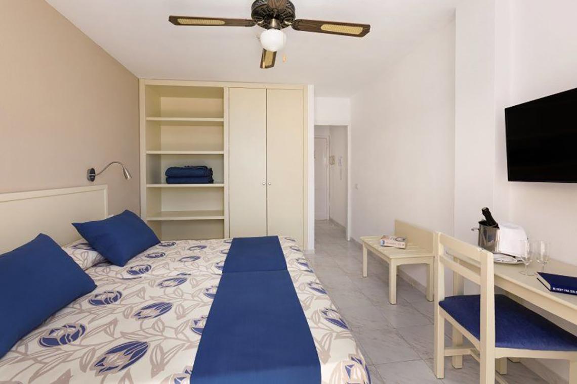 Innenansicht eines Zimmers im Hotel Bahia Flamingo mit Bett, Schreibtisch und Fernseher.