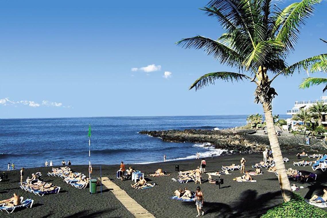 Strand am Bahia Flamingo Hotel mit vielen Sonnenliegen und einer Palme
