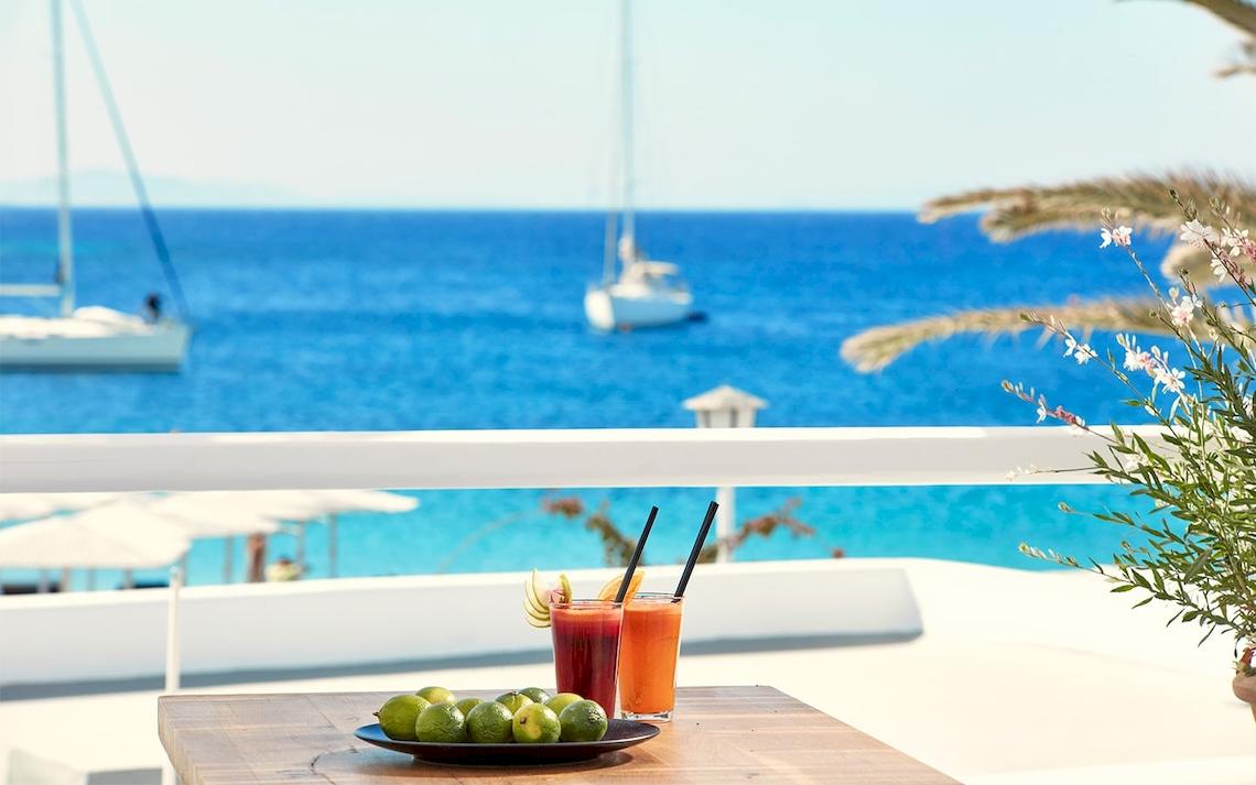 Terrasse des Mykonos Ammos Hotels mit Blick auf das Meer und Cocktails.