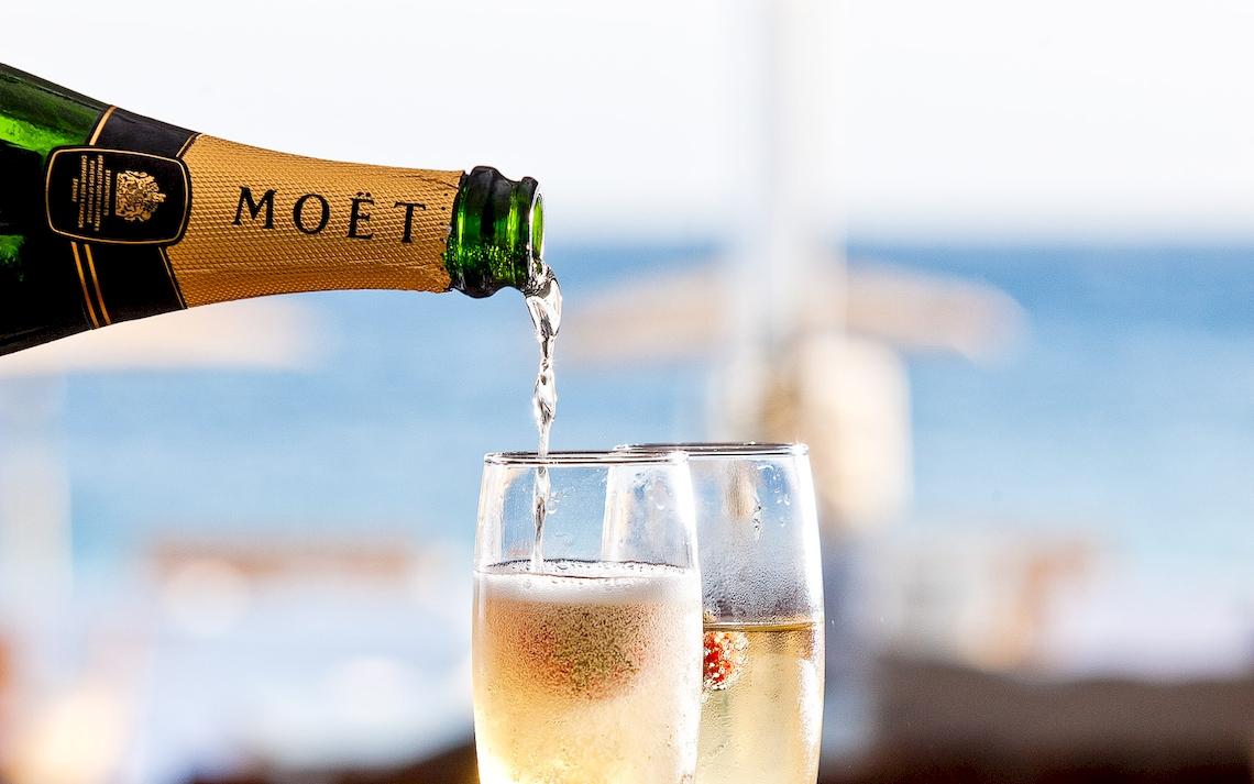 Moët Champagne wird in zwei Gläser gegossen, am Strand.