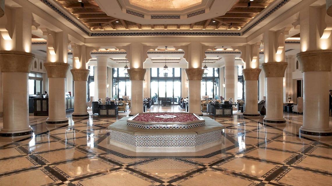 Das geräumige Foyer des Jumeirah Mina A'Salam Hotels mit hohen Säulen und einem runden Brunnen in der Mitte.