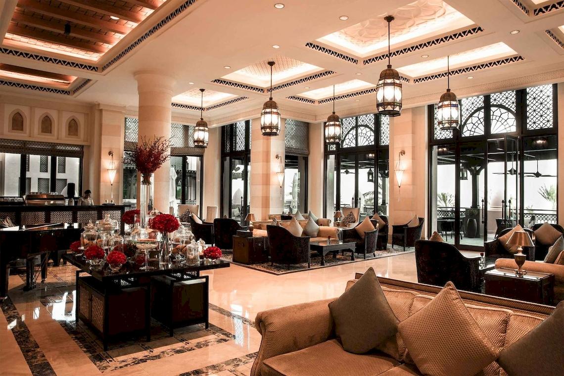 Lobby des Jumeirah Mina A'Salam Hotels mit elegantem Interieur, Sofas, Tischen und Kronleuchtern.