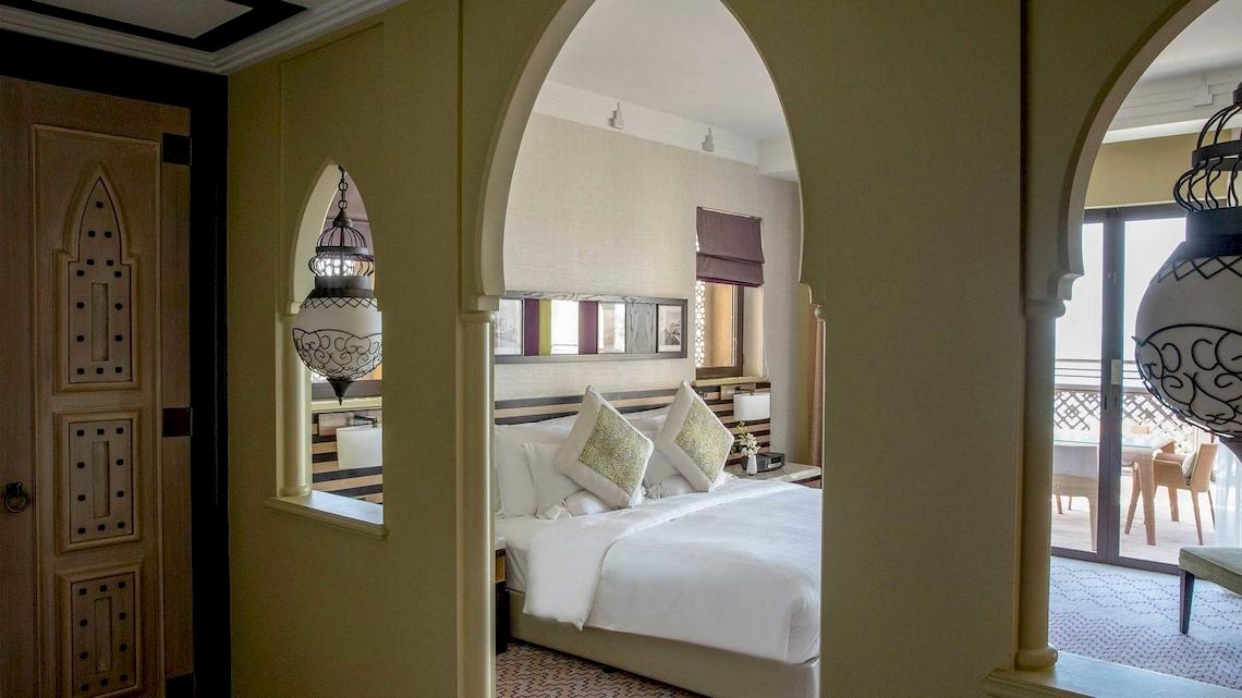 Ein Blick in das Hotelzimmer im Jumeirah Mina A'Salam mit einem großen Bett und Dekor.