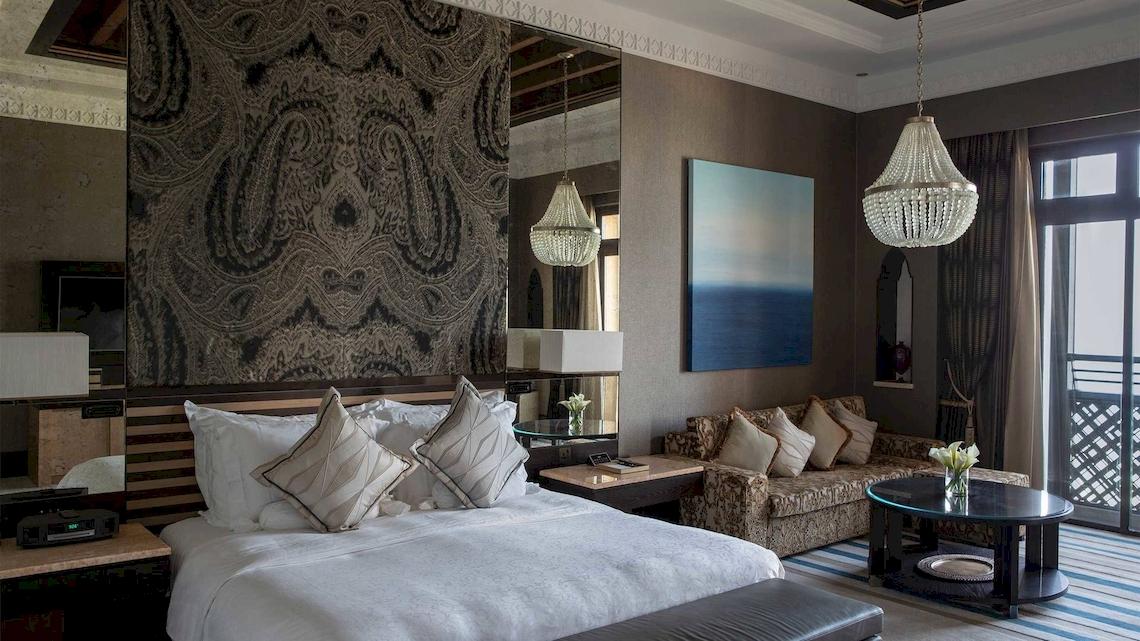 Innenansicht eines Schlafzimmers im Jumeirah Mina A'Salam Hotel mit Bett, Lampen und Dekor.