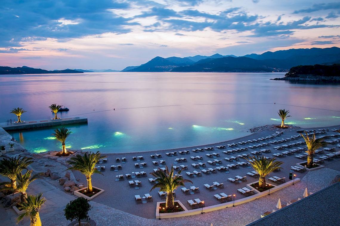 Abendlicher Blick auf den Strand des Dubrovnik President Valamar Collection mit vielen Liegen und Palmen.