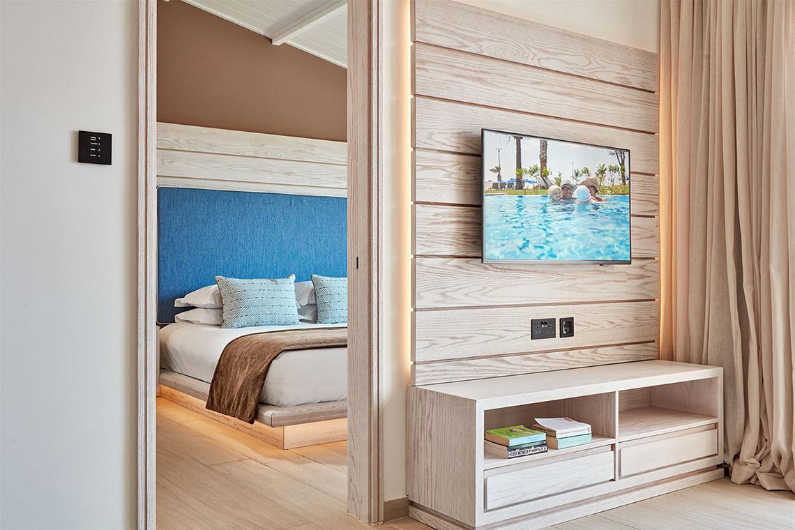Innenansicht eines Zimmers im Mare Ayia Napa Hotel mit Bett, Fernseher und offenem Eingang.