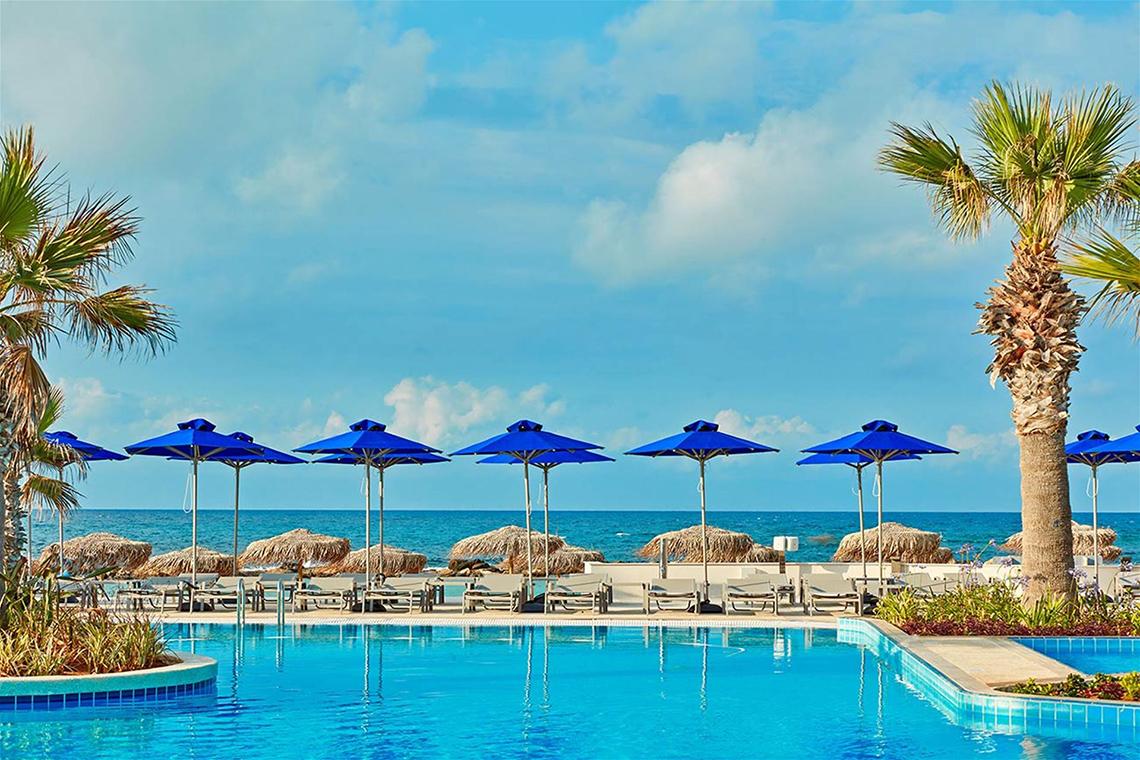 Außenpool im Mare Ayia Napa Hotel mit blauen Sonnenschirmen und Palmen