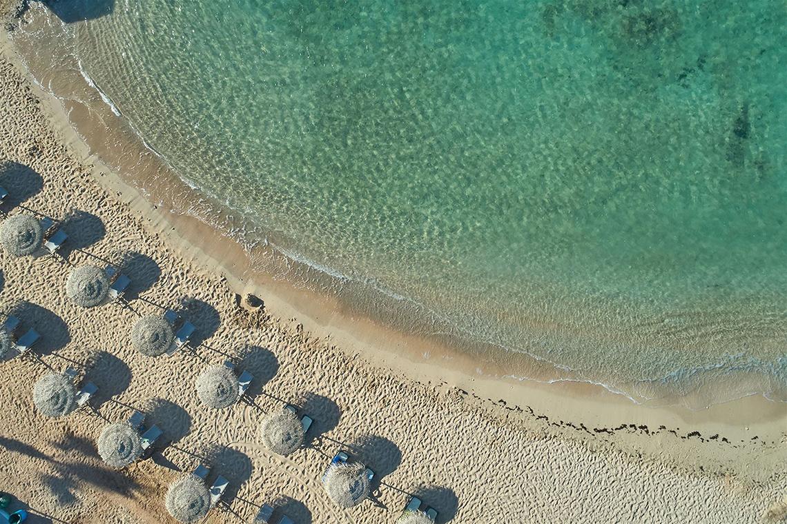Luftaufnahme des Mare Ayia Napa Strandes mit Sonnenschirmen und Strandliegen
