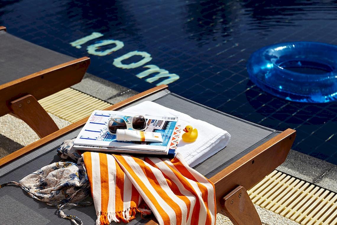 Loungestuhl am Pool des Sunwing Kamala Beach Hotels mit Zeitschriften, Sonnencreme und Badespielzeug
