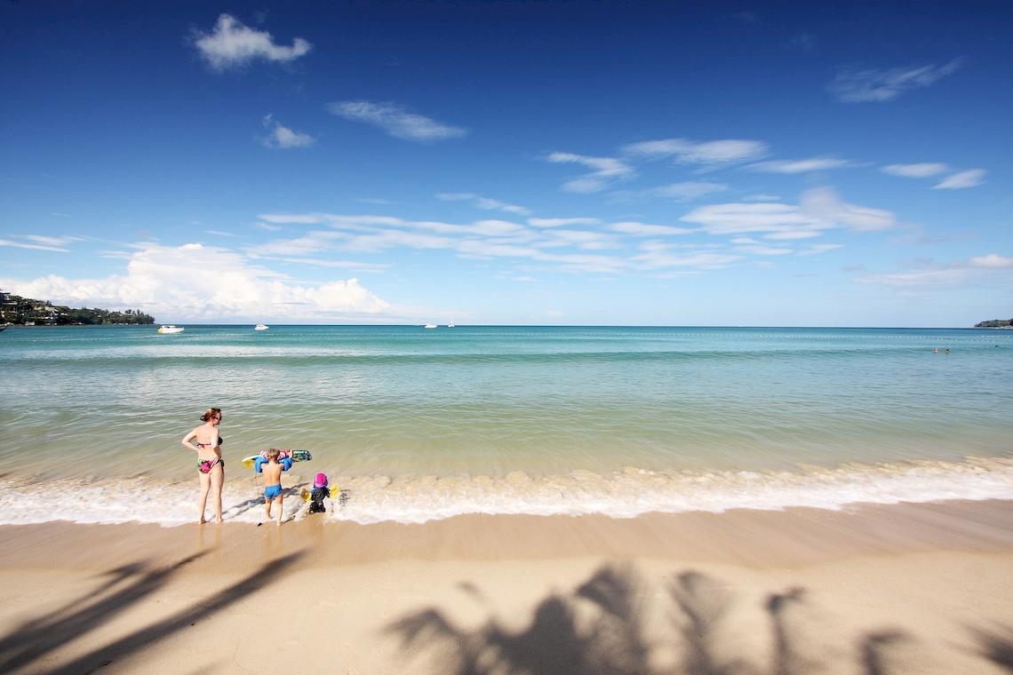 Familie auf dem Strand mit Blick auf das Meer und blauen Himmel
