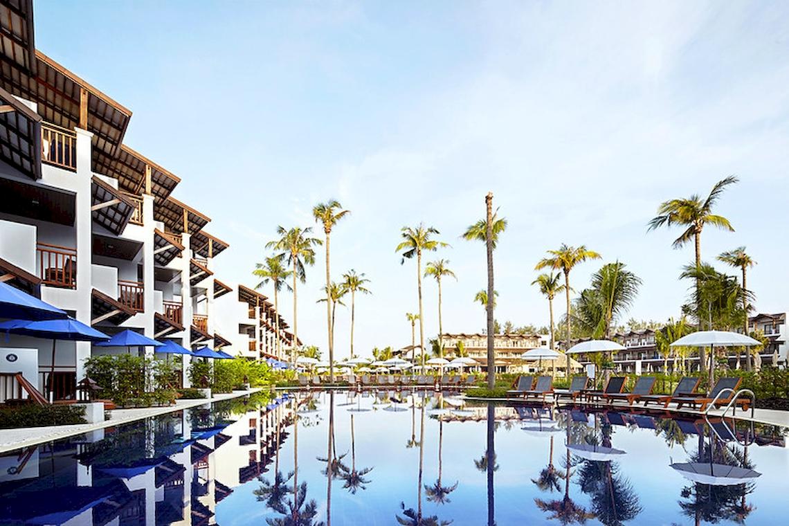 Außenansicht des Sunwing Kamala Beach Hotels mit Pool, Palmen und Sonnenliegen