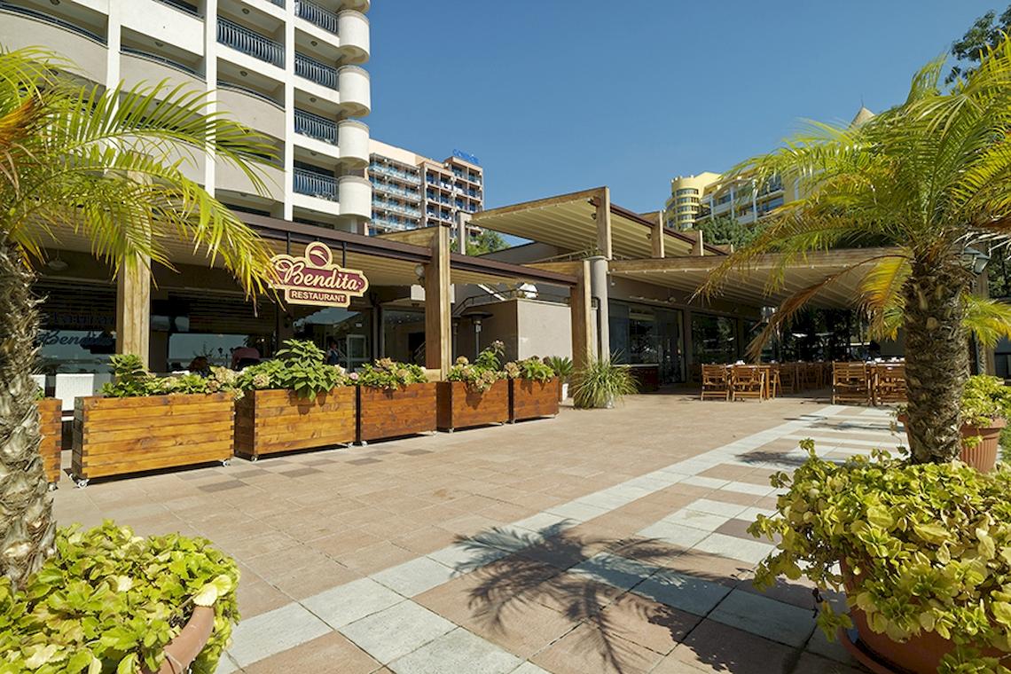 Terrasse des Bellevue Hotels mit Tischen und Palmen im Freien