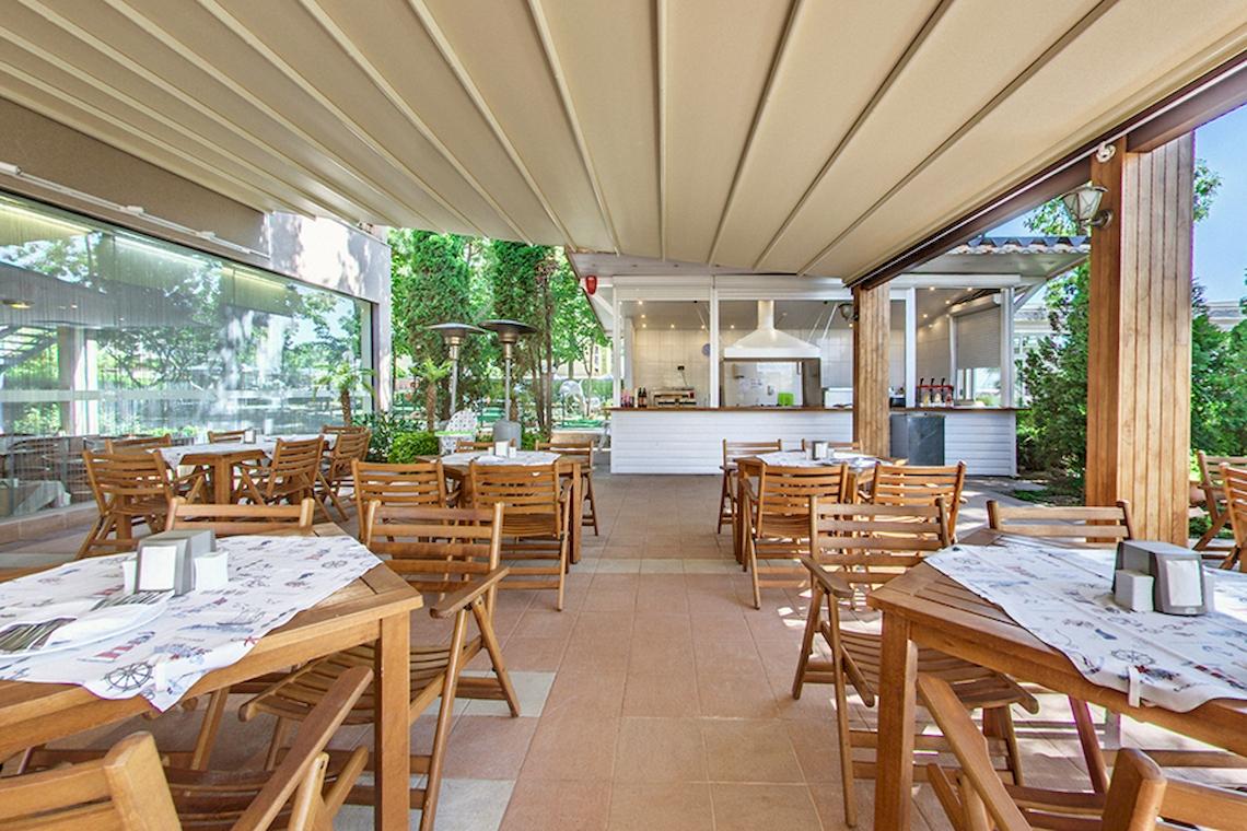 Terrasse des Bellevue Hotels mit braunen Holztischen und Stühlen.