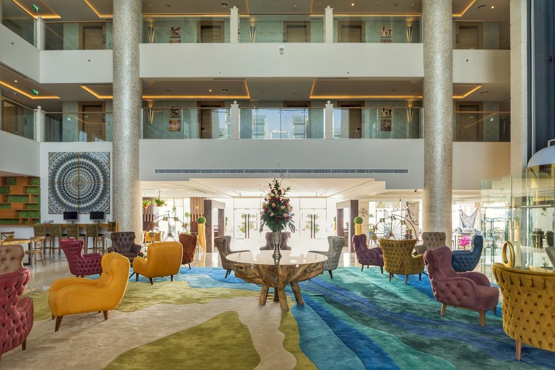 Lobby des Royal Central Hotel The Palm mit bunten Sesseln und einem runden Tisch.