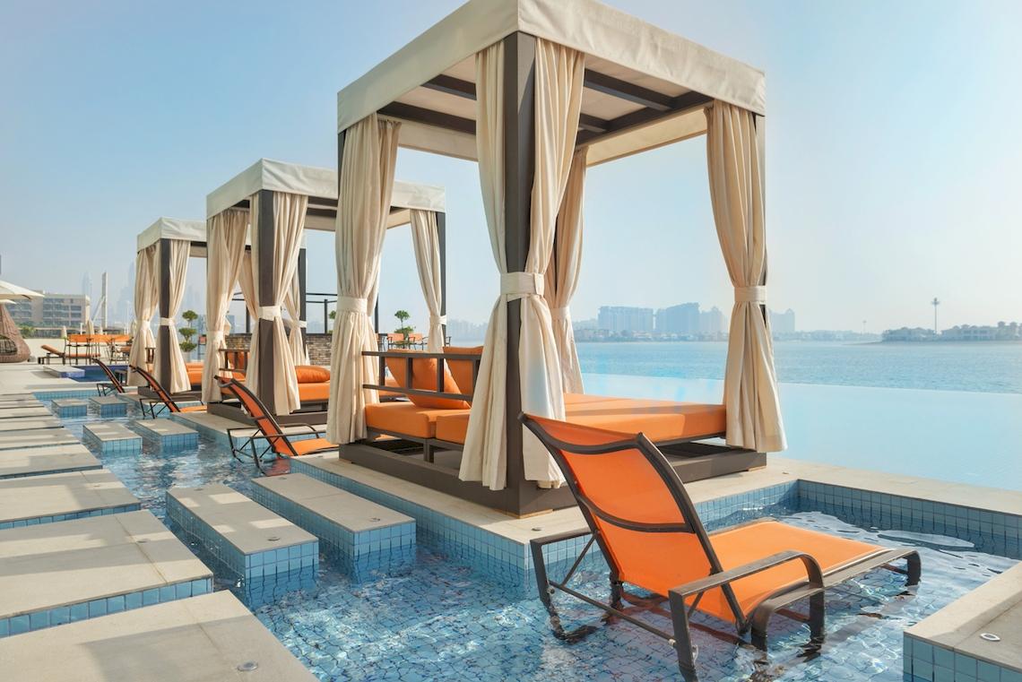 Royal Central Hotel The Palm - Lounges am Pool mit orangefarbenen Sesseln und weißen Vorhängen.