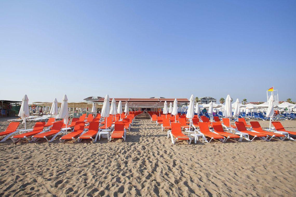 Strand mit roten Liegestühlen und weißen Sonnenschirmen im Freien, Side Orange Palace Hotel