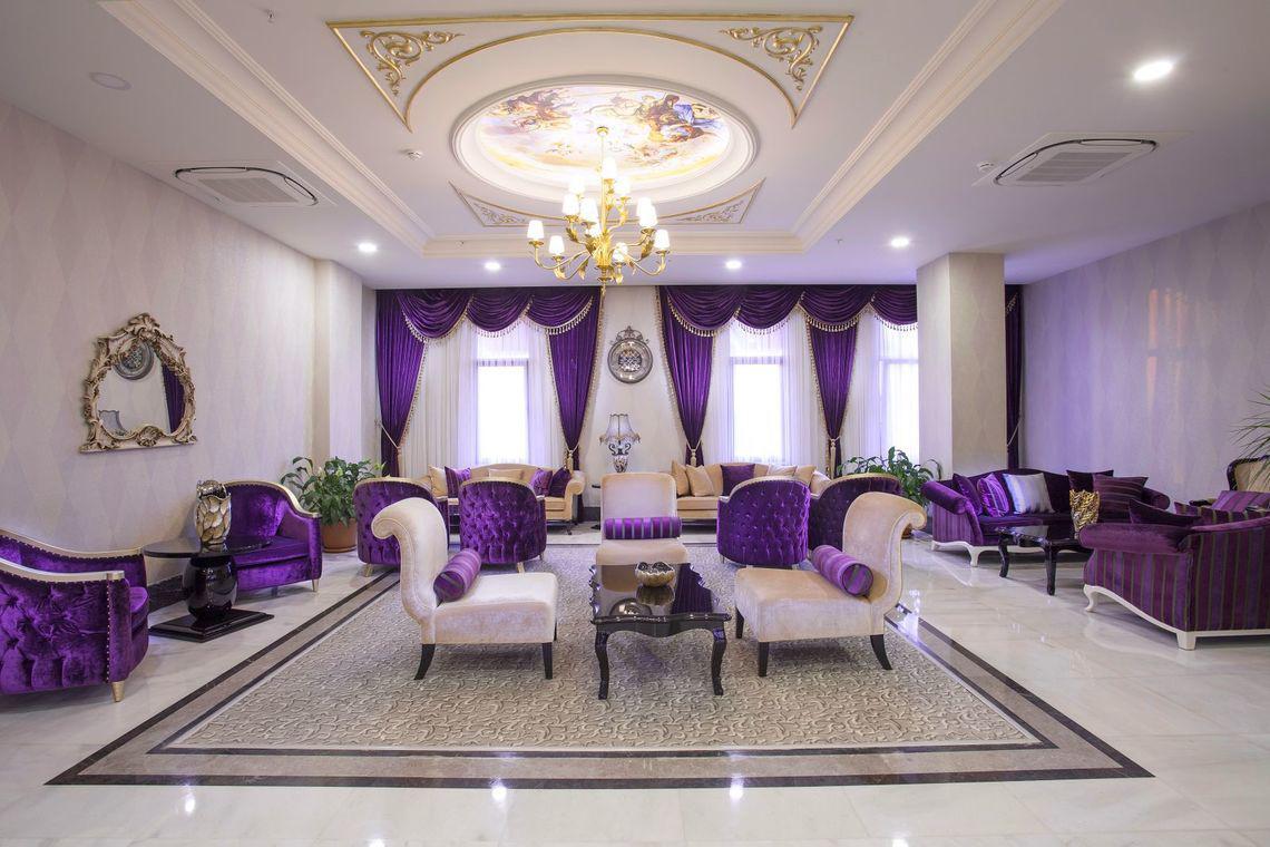 Lobby des Side Orange Palace Hotels mit violetten Möbeln und Deckenleuchte.