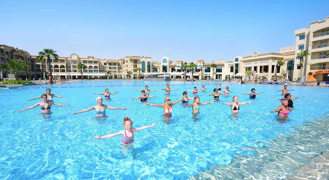 Gruppe von Menschen, die im großen Pool des Pickalbatros White Beach Resort Aqua-Gymnastik machen.
