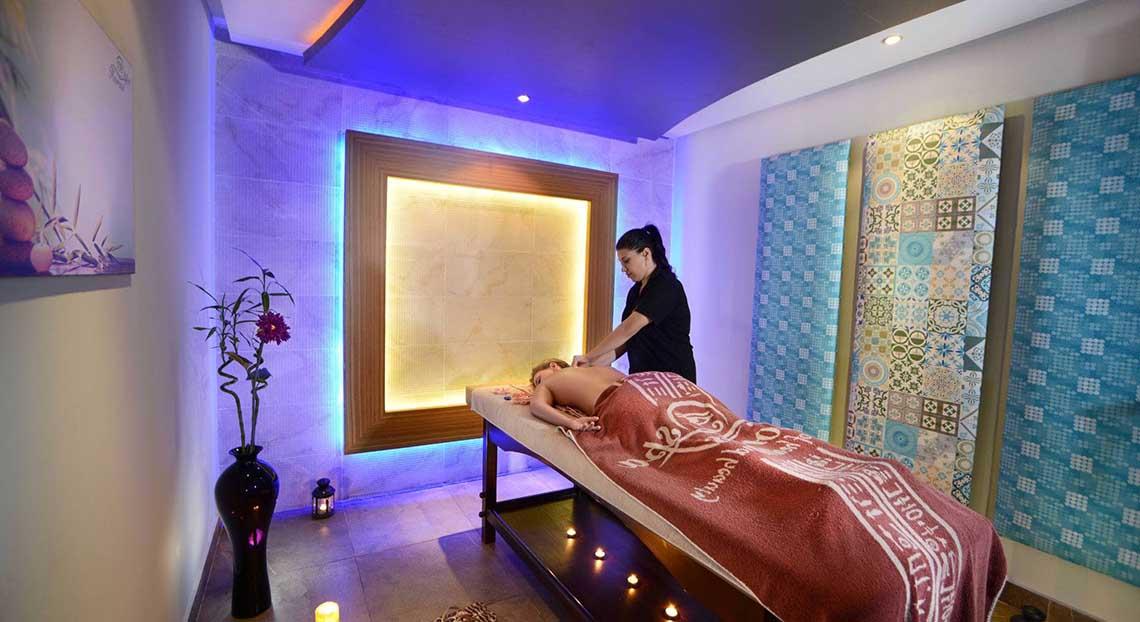 Eine Frau im schwarzen T-Shirt führt eine Massage in einem Hotelbehandlungsraum durch.